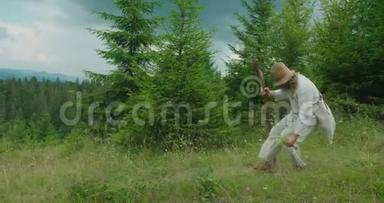 这位穿着旧衣服的<strong>老人</strong>在拐杖的帮助下<strong>走路</strong>，拿起花。 在山上。